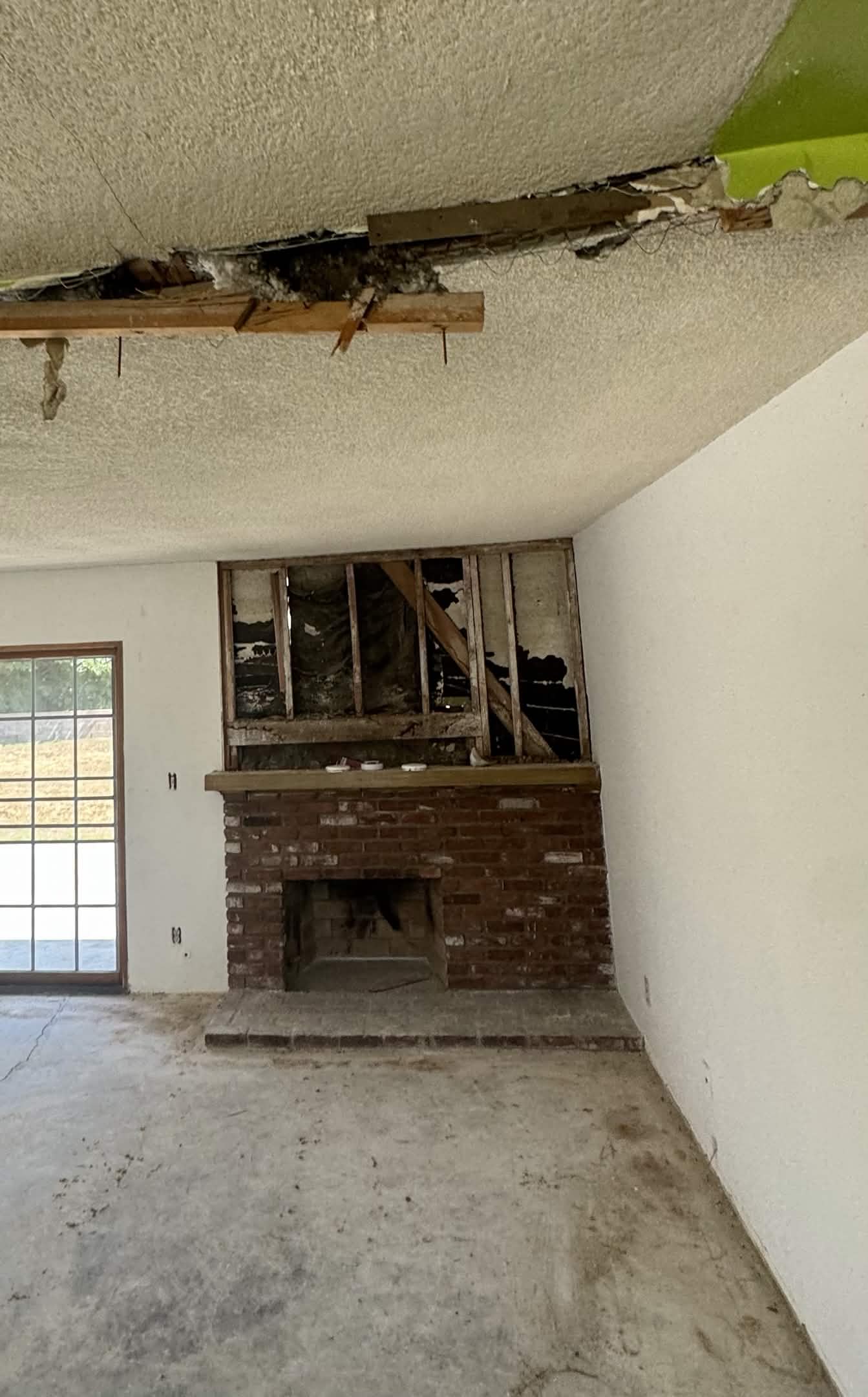 Old brick fireplace with damaged ceiling