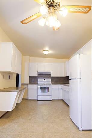 Outdated kitchen with white cabinets and old appliances