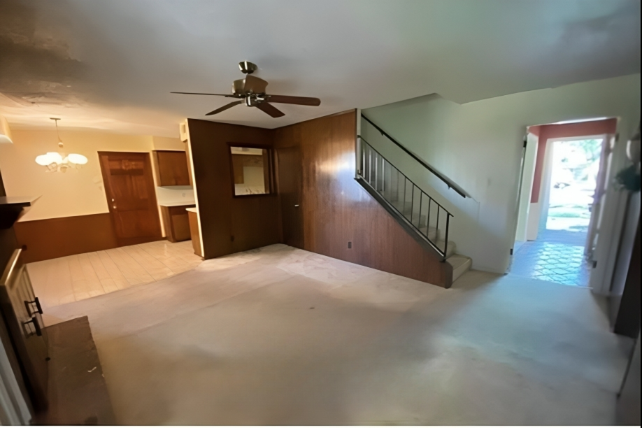 Dated living room with wood paneling and old carpet