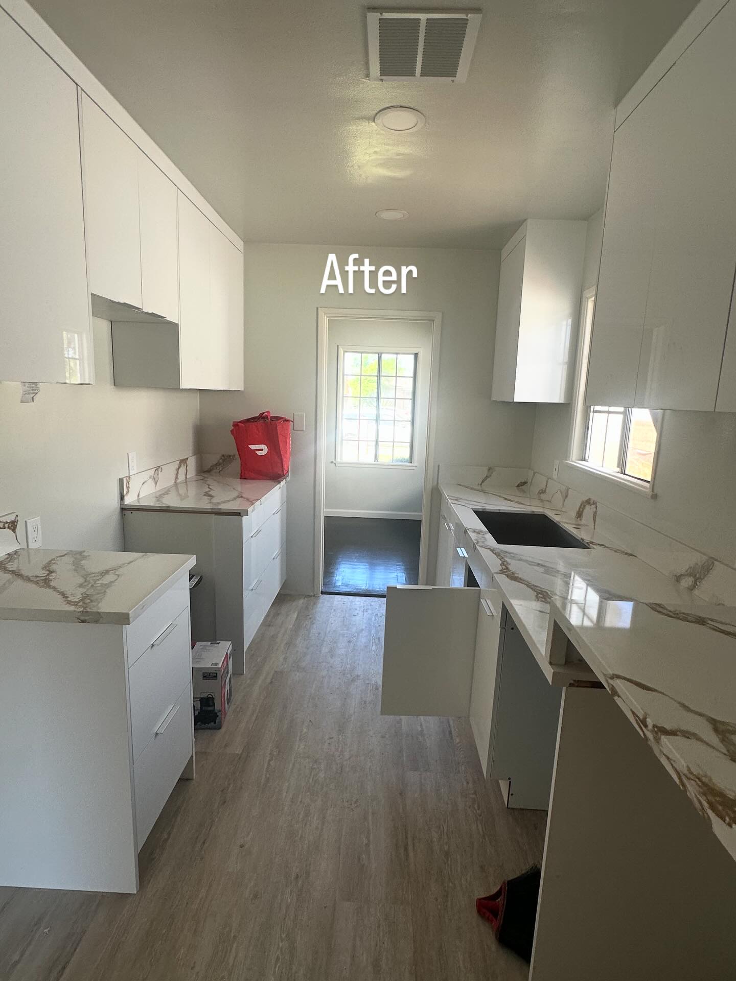 Kitchen after renovation with white cabinetry and marble countertops